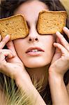Young woman covering eyes with rusks