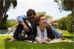 Young couple lying on grass reading book during summer holidays, Sardinia, Italy