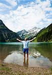 Mature man with arms stretched outward, standing in Lake Vilsalpsee, Tannheim Valley, Austria