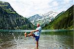 Mature man standing in lake, kicking water, Lake Vilsalpsee, Tannheim Valley, Austria