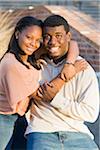 Young couple embracing outdoors on college campus, smiling and looking at camera, Florida, USA