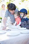 Boys and grandmother setting dinner table outdoors