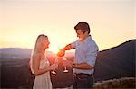 Young couple having champagne outdoors at sunset