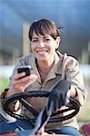 Woman on vehicle with cellphone in plant nursery