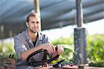 Young man on vehicle in plant nursery