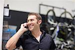 Mid adult man on cellphone in bike shop