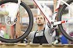 Young man holding bicycle in repair shop