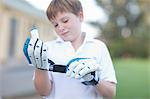 Boy putting on cricket gloves