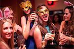 Young women with drinks wearing masks at hen party