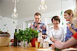 Mother with grown up children preparing food in kitchen