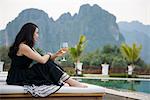 Woman with wine glass by poolside, Vang Vieng, Laos