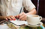 Woman writing postcard in cafe