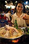 Woman using chopsticks in Korean restaurant, Luang Prabang, Laos