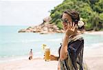 Woman using mobile phone on beach, Banyon Tree Resort, Ko Samui, Thailand