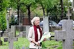 Senior woman holding flowers in graveyard