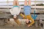 Girlfriends hanging upside down from pier