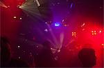 Nightclub scene with people dancing, disco ball, lighting equipment