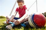 Boy sitting on field tying shoe lace