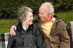 Husband and wife sharing a light moment on bench in field