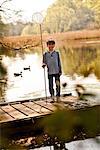 Boy standing on pier holding fishing nets, portrait