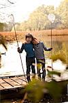 Brothers standing together on pier holding fishing nets, portrait