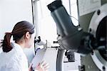 Female scientist looking through microscope