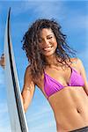 Beautiful young woman surfer girl in bikini with surfboard standing on a beach