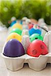 Colorful painted Easter eggs in a carton on the green background