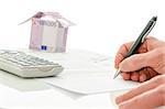 Contract signing of house sale with money house in the background. On a white table.