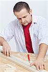 Woodwork - man measuring wooden planck on workbench
