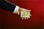 Male hand holding playing cards over red background.