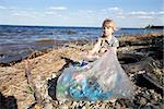 small girl collecting rubbish near the river