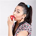 A woman is biting a red apple