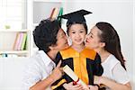 Kindergarten graduation. Asian family, grandparent and parent kissing grandchild on her kinder graduate day.