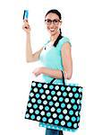 Smiling attractive woman holding cerdit-card with shopping bags wearing eyeglasses