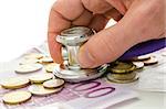 Male hand holding stethoscope on European currency. Concept of financial crisis solution.