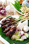 Satay or sate, skewered and grilled meat, served with peanut sauce, cucumber and ketupat. Traditional Malaysian food. Hot and spicy Malay dish, Asian cuisine.