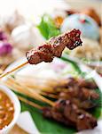 Satay or sate, skewered and grilled meat, served with peanut sauce, cucumber and ketupat. Traditional Malay food. Hot and spicy Malaysian dish, Asian cuisine.