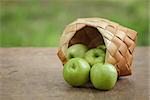 green apples in a birchbark basket, on wooden table