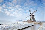 Dutch windmill by canal in winter
