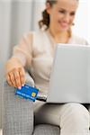 Closeup on credit card in hand of woman using laptop