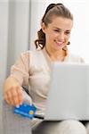 Smiling young housewife with laptop and credit card