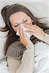 Woman lying on sofa and blowing nose in the living room