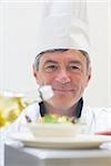 Chef preparing a salad with oil in the kitchen