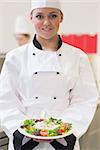 Cheerful chef showing her salad in the kitchen