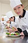 Smiling chef preparing salad in culinary class in kitchen