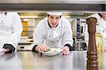 Chef garnishing his salad and smiling in the kitchen