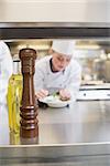 Pepper grinder and olive oil on the counter of busy kitchen