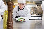 Happy chef presenting her salad in the kitchen