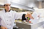 Chef garnishing his cake with a mint leaf in the kitchen